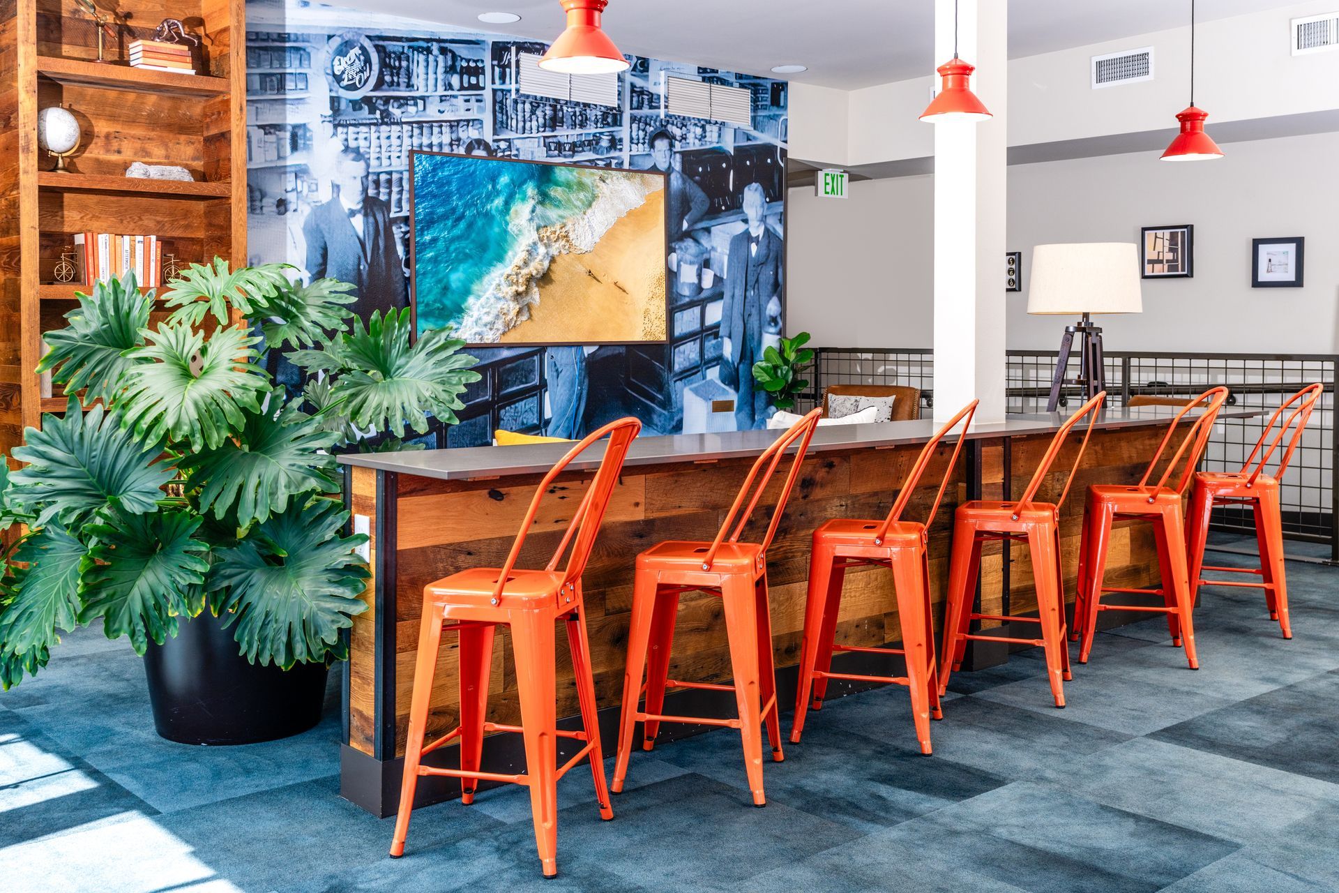 A row of orange stools are lined up next to a wooden table in a room.