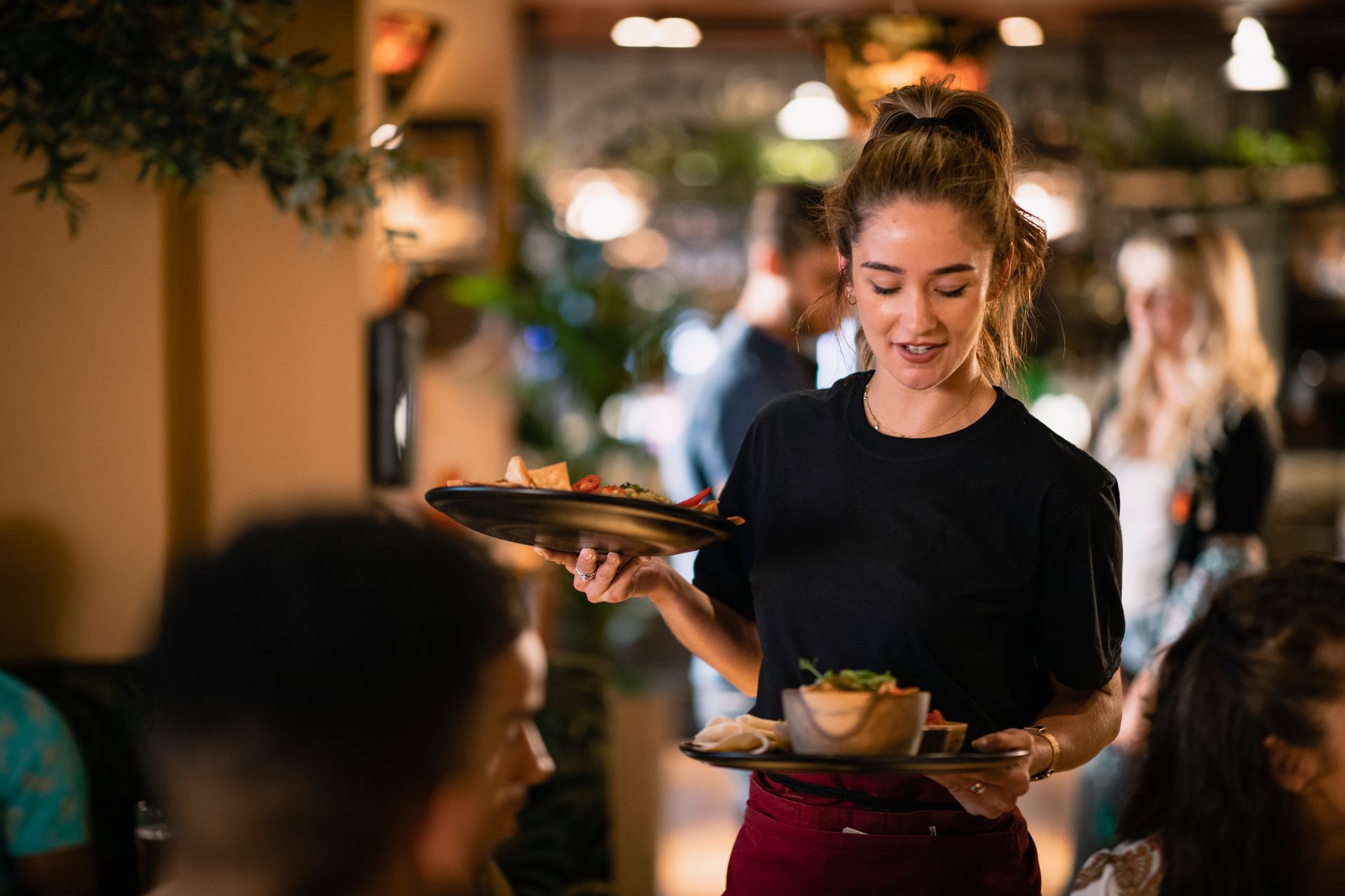 A waitress is holding a tray of food in a restaurant.