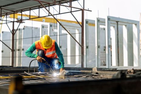A construction worker is welding a piece of metal on a construction site.