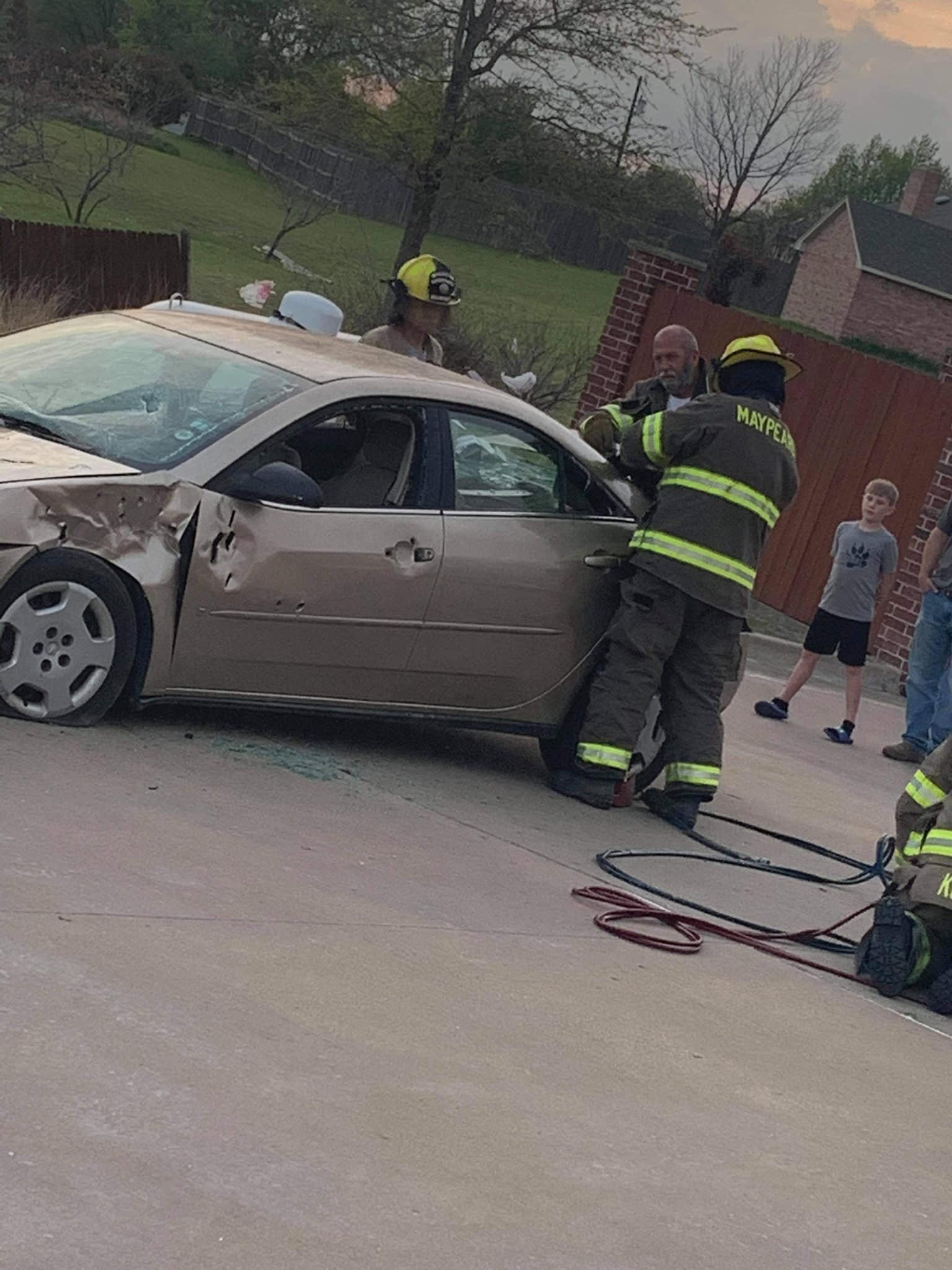 A group of firefighters are training on extrication on a damaged car.