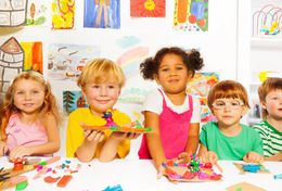 A group of children are sitting at a table making crafts.