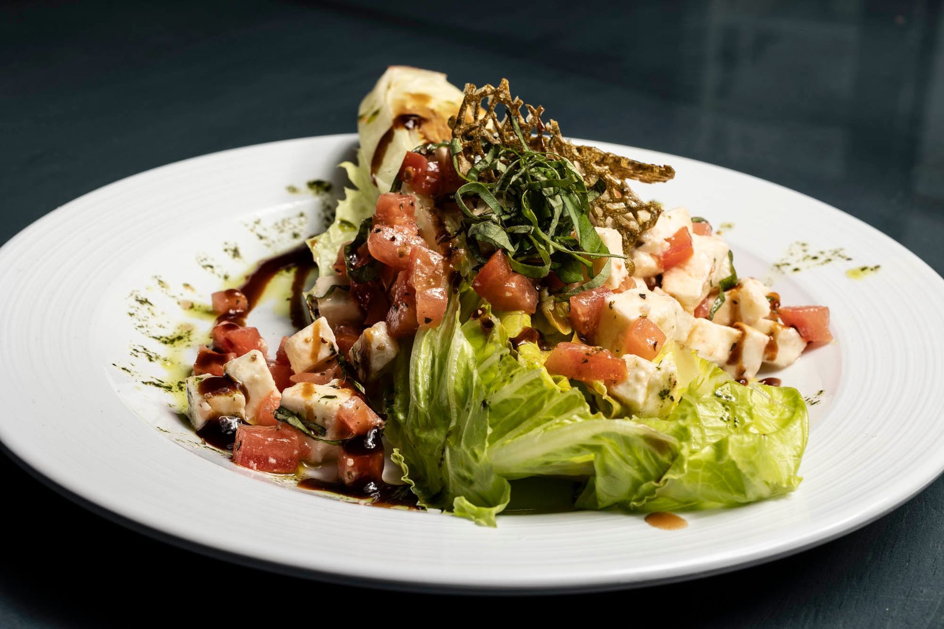 A white plate topped with a salad of lettuce , tomatoes and cheese.