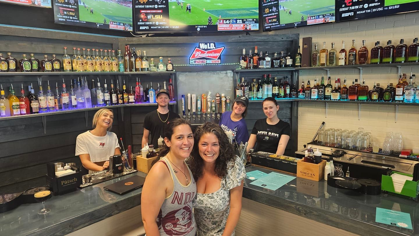 Employees are standing behind and in front of the bar.