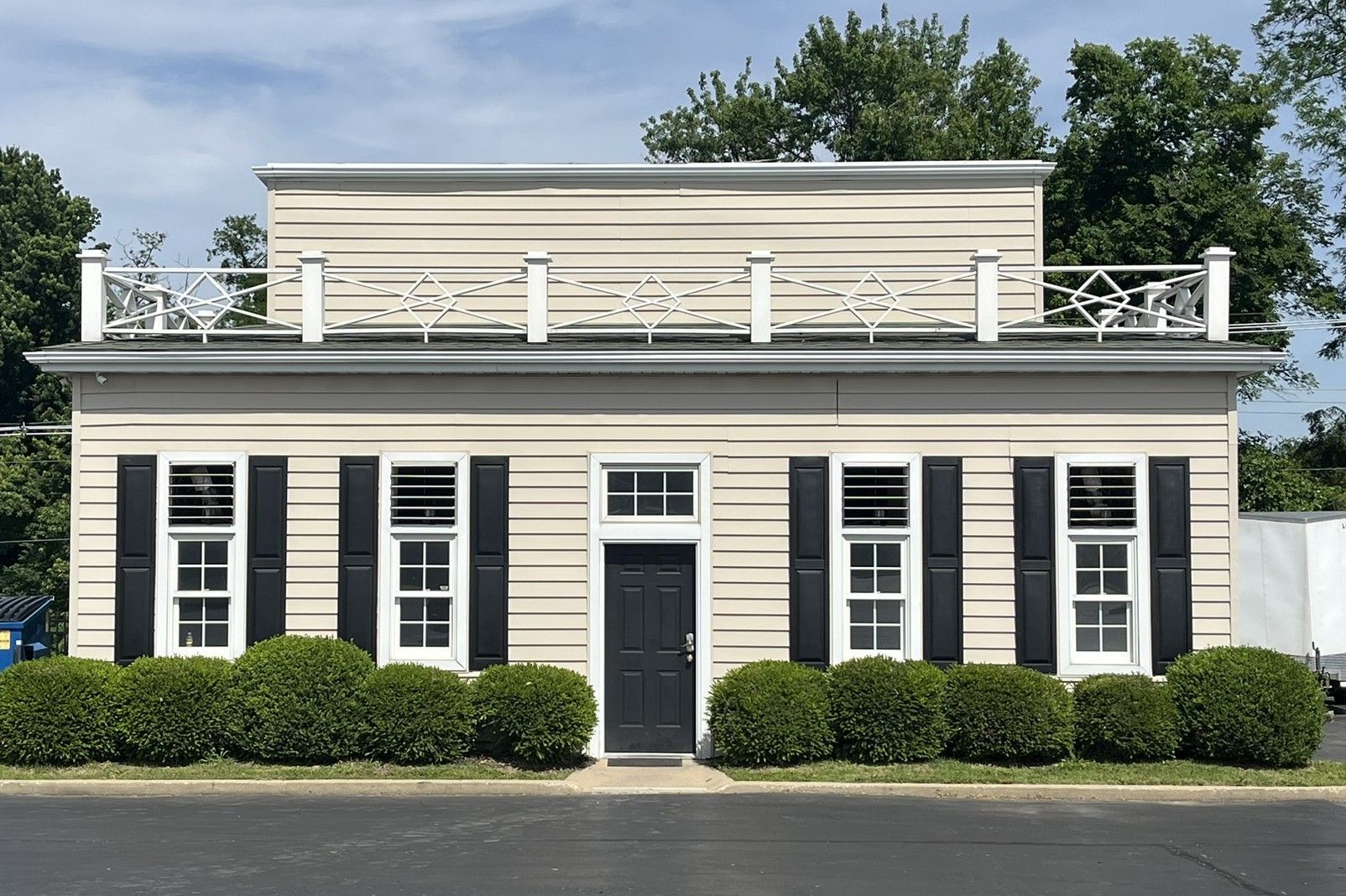 Historic cream-colored building with black shutters and white trim, viewed from the street.