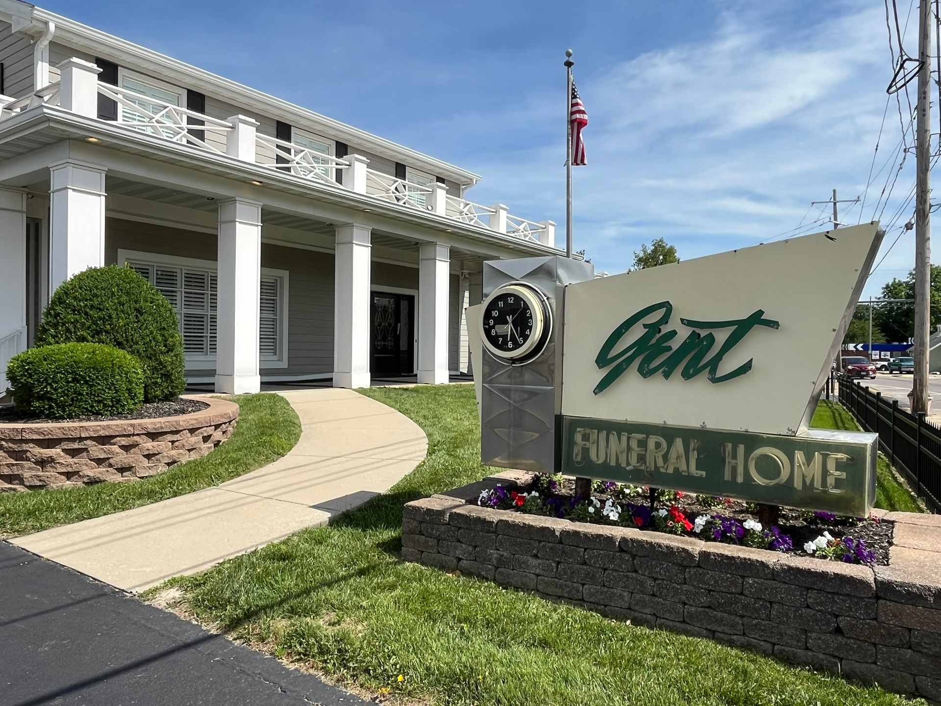 Giant Memorial Home sign in front of a white building with columns and an American flag under a blue sky