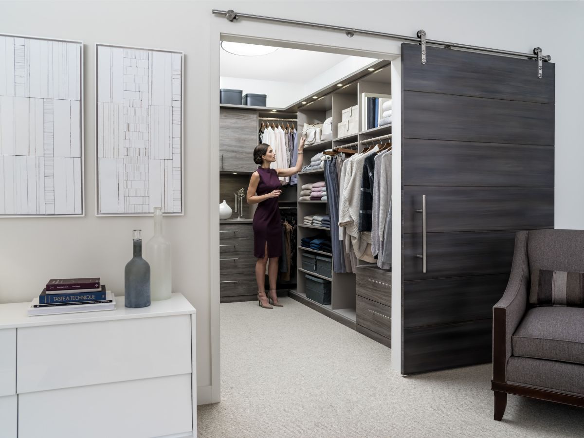 A woman is standing in a walk in closet with a sliding barn door.