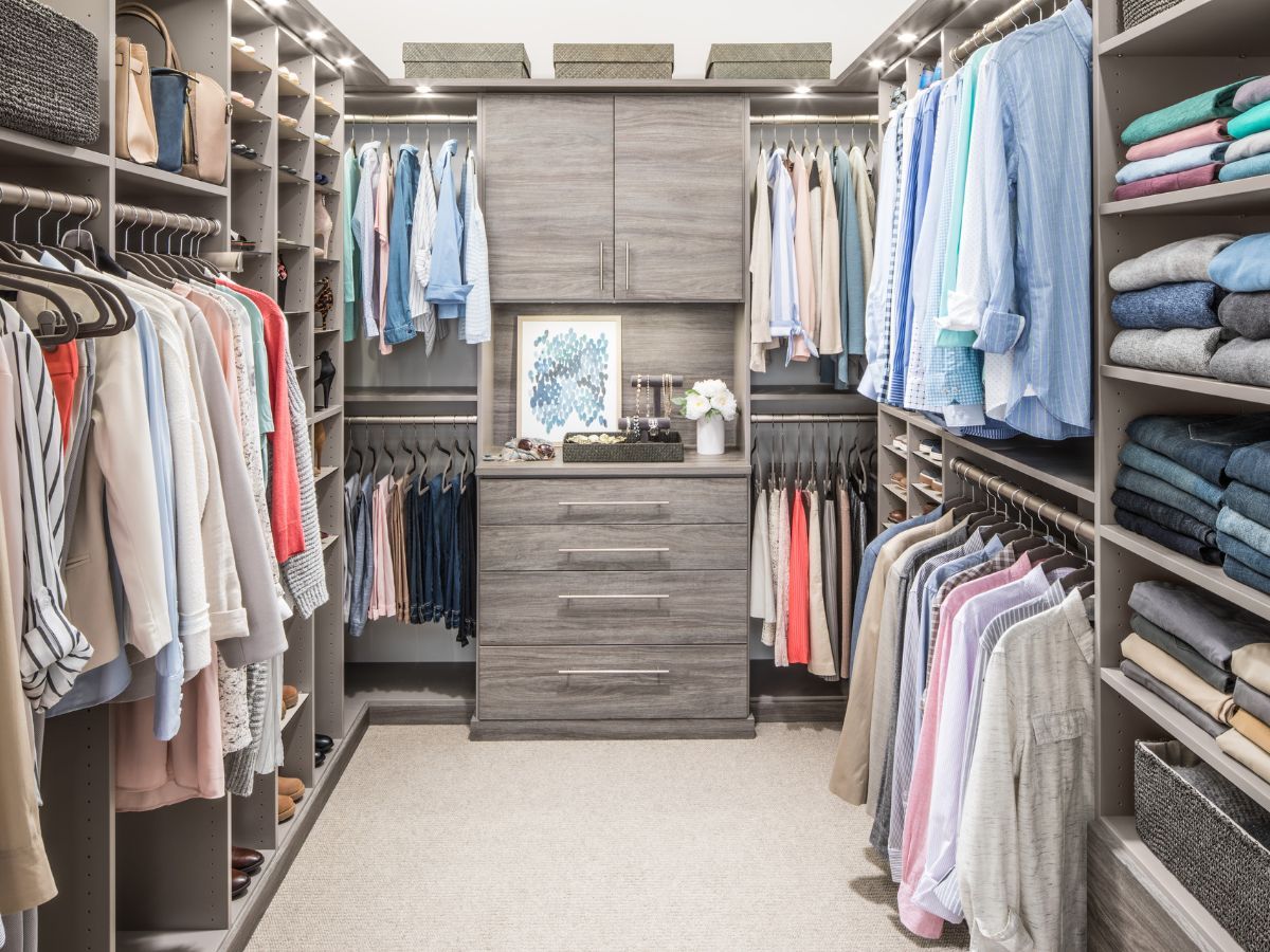 A walk in closet filled with lots of clothes and a dresser.