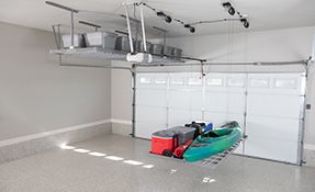 A kayak is hanging from the ceiling of a garage.