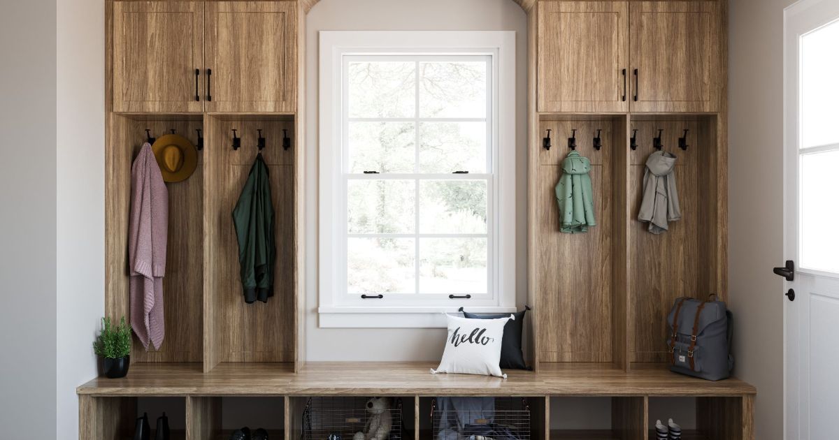 A mud room with wooden cabinets , a bench , and a window.