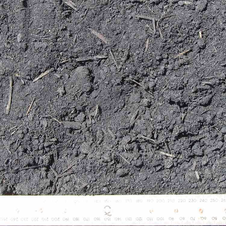 Dark, Textured Soil With Visible Wood Chips and a Ruler — Kuranda Landscape Supplies in Kuranda, QLD