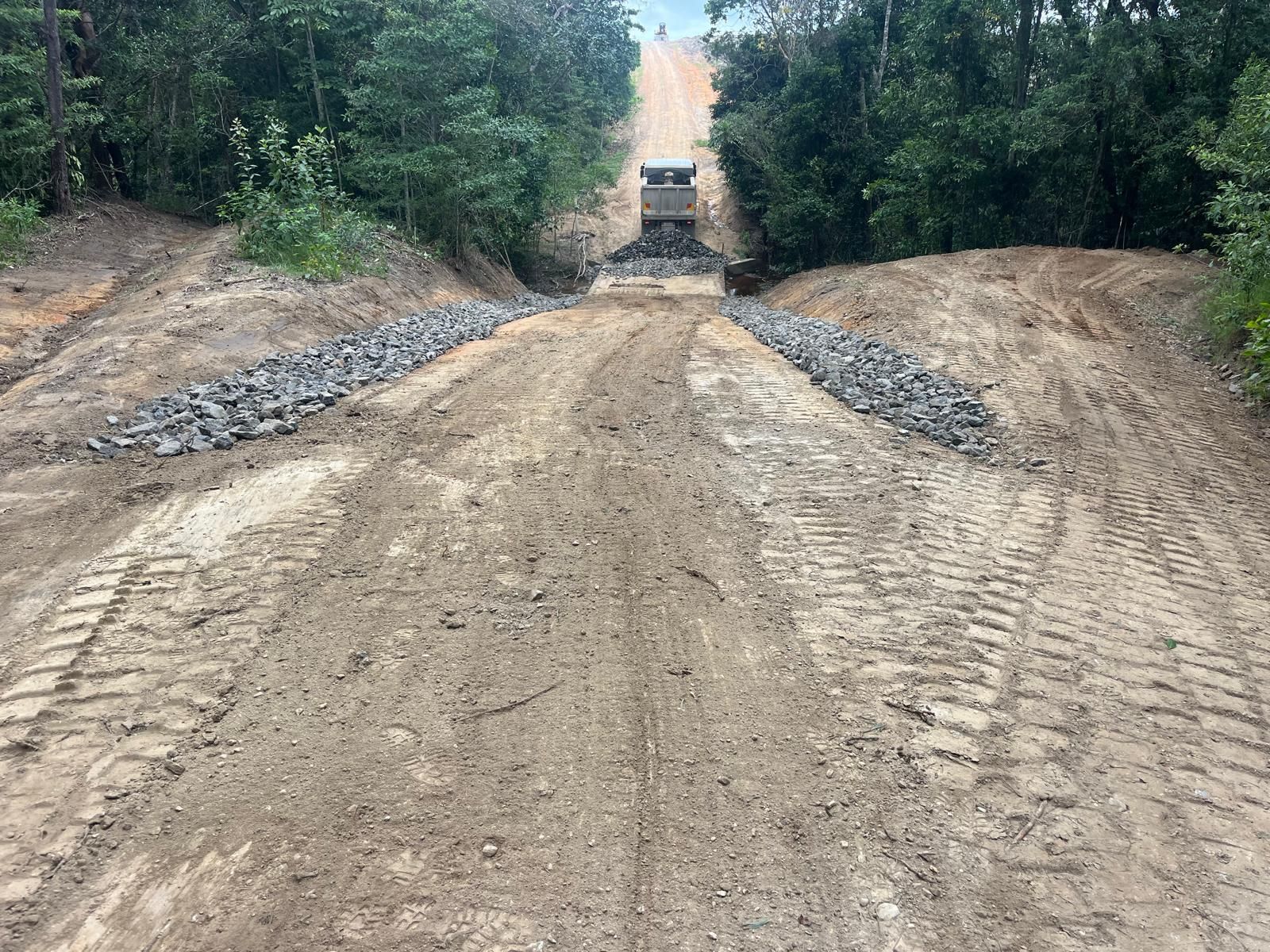 Dirt road with tire tracks and rock borders leading uphill; construction setting — Kuranda Landscape Supplies in Kuranda, QLD