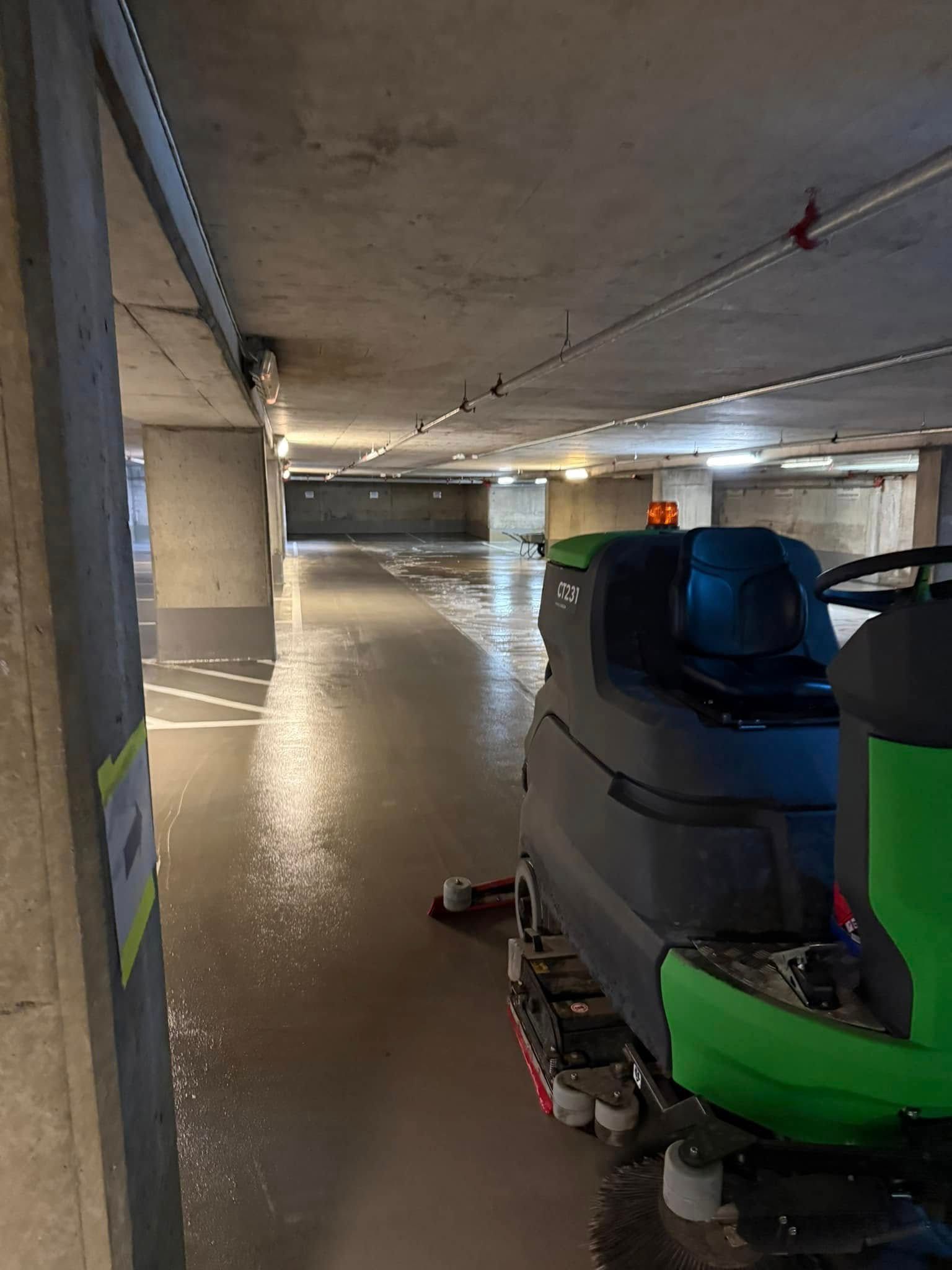 Kjellergarasje med en blå og grønn gulvrengjøringsmaskin til høyre.