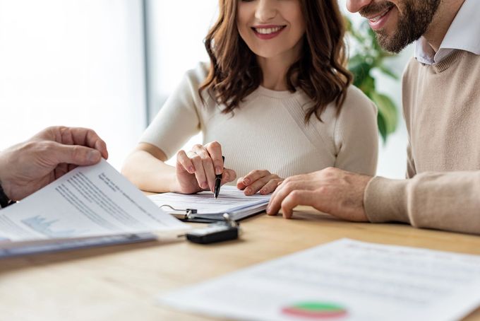 A man and a woman are sitting at a table signing a document.