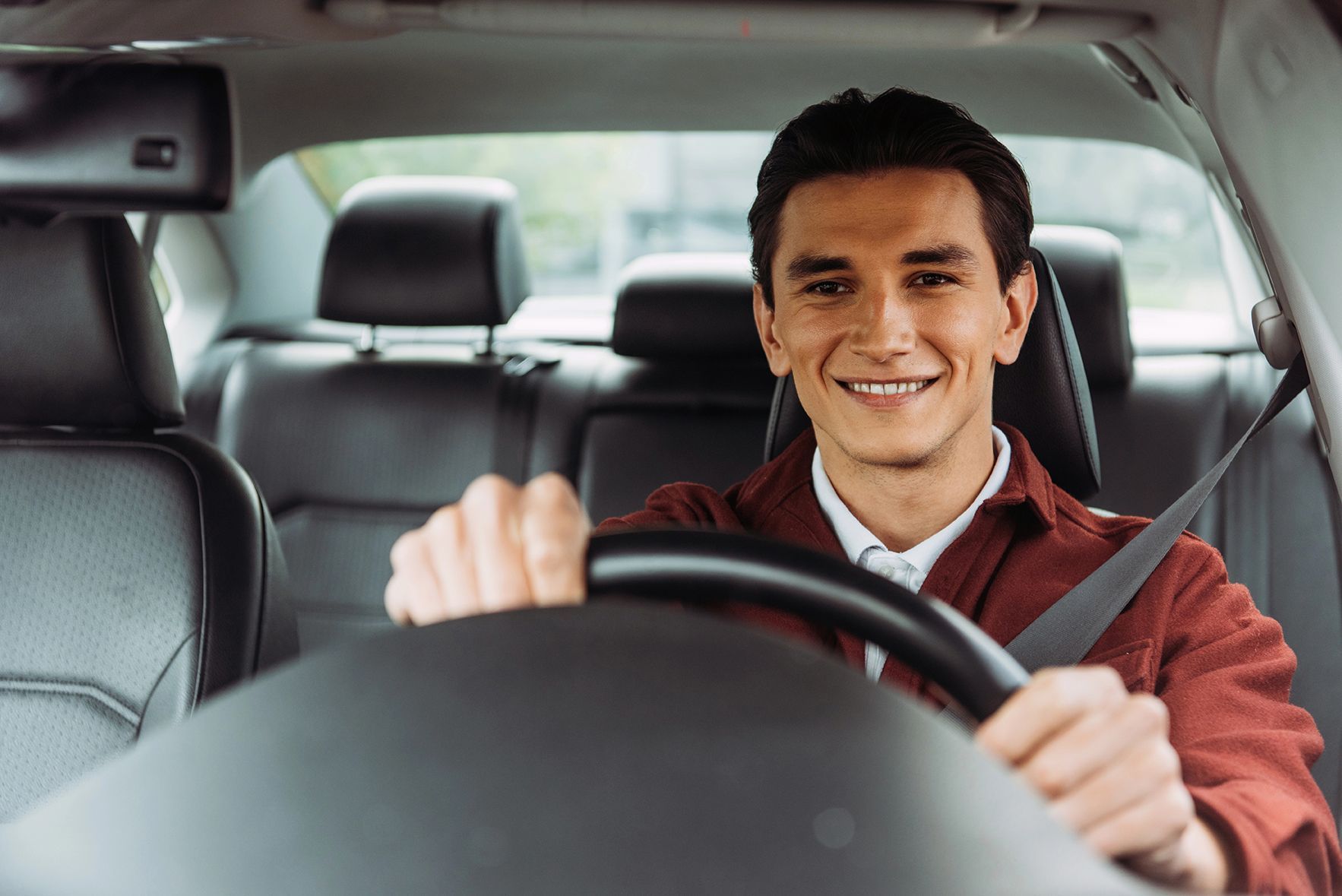 A man is sitting in the driver 's seat of a car and smiling.