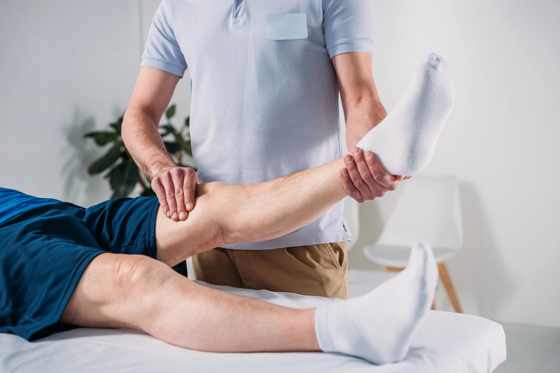 Un fisioterapista esegue esercizi di stretching sulla gamba di un paziente in una luminosa stanza della clinica.