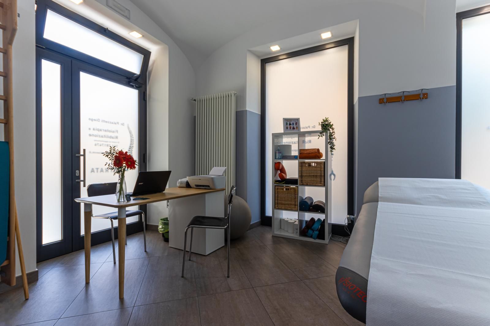 Camera moderna e minimalista con scrivania, sedia, mensola e letto singolo accanto a una grande finestra.