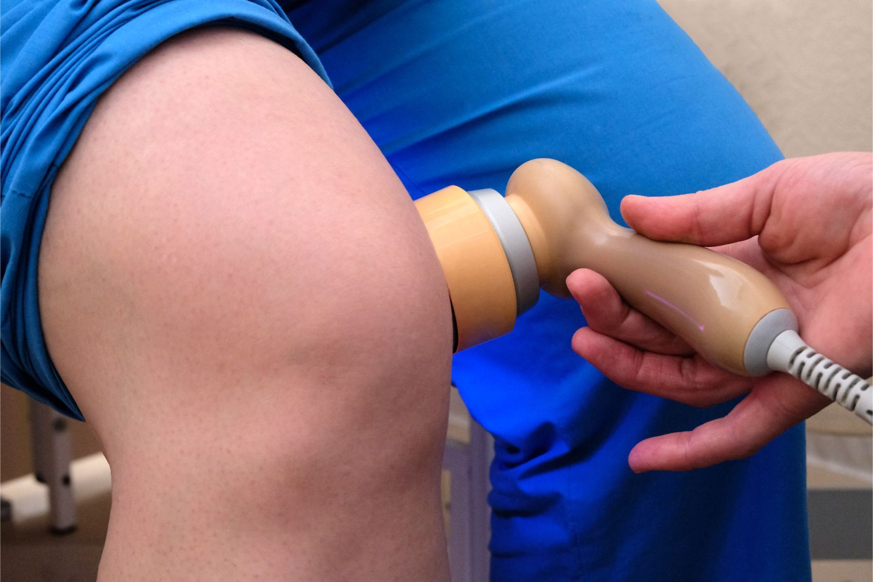 Trattamento di fisioterapia sulla gamba flessa di una persona con una sonda a ultrasuoni fissata alla coscia.