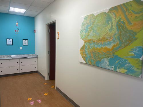 Bright hallway with blue accent wall, abstract wall art, and paw-print decals on the floor