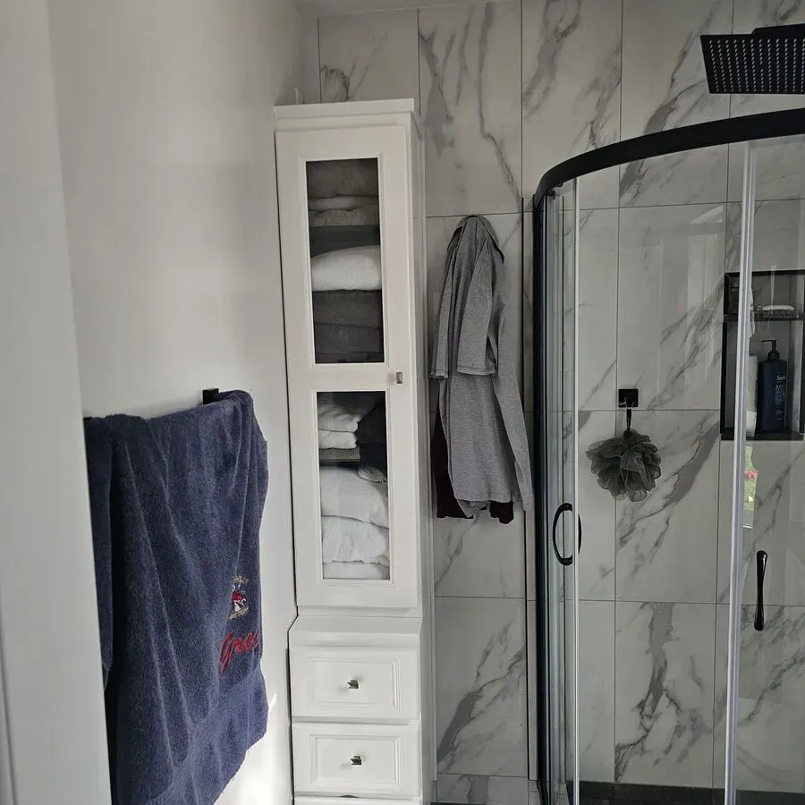 A bathroom with a towel hanging on the wall and a shower stall.