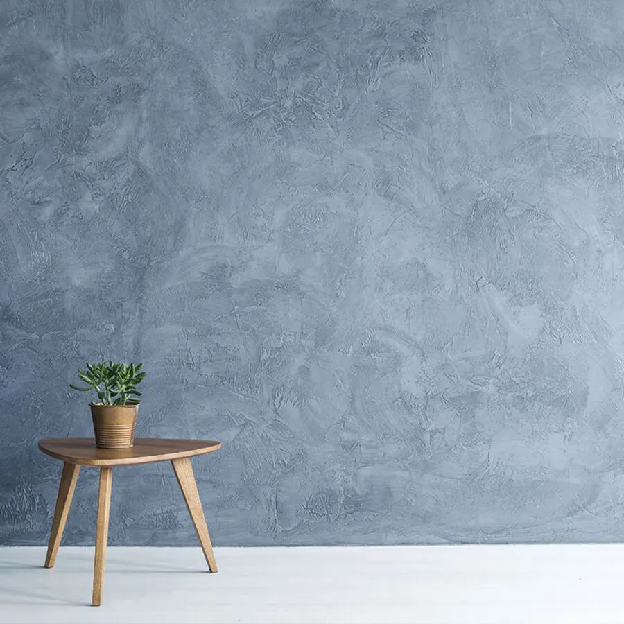 A wooden table with a potted plant on it in front of a blue wall.