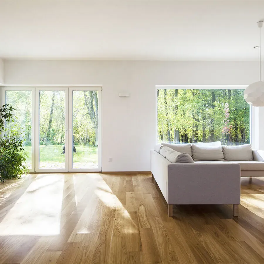 A living room with a couch and a large window with a view of a forest.