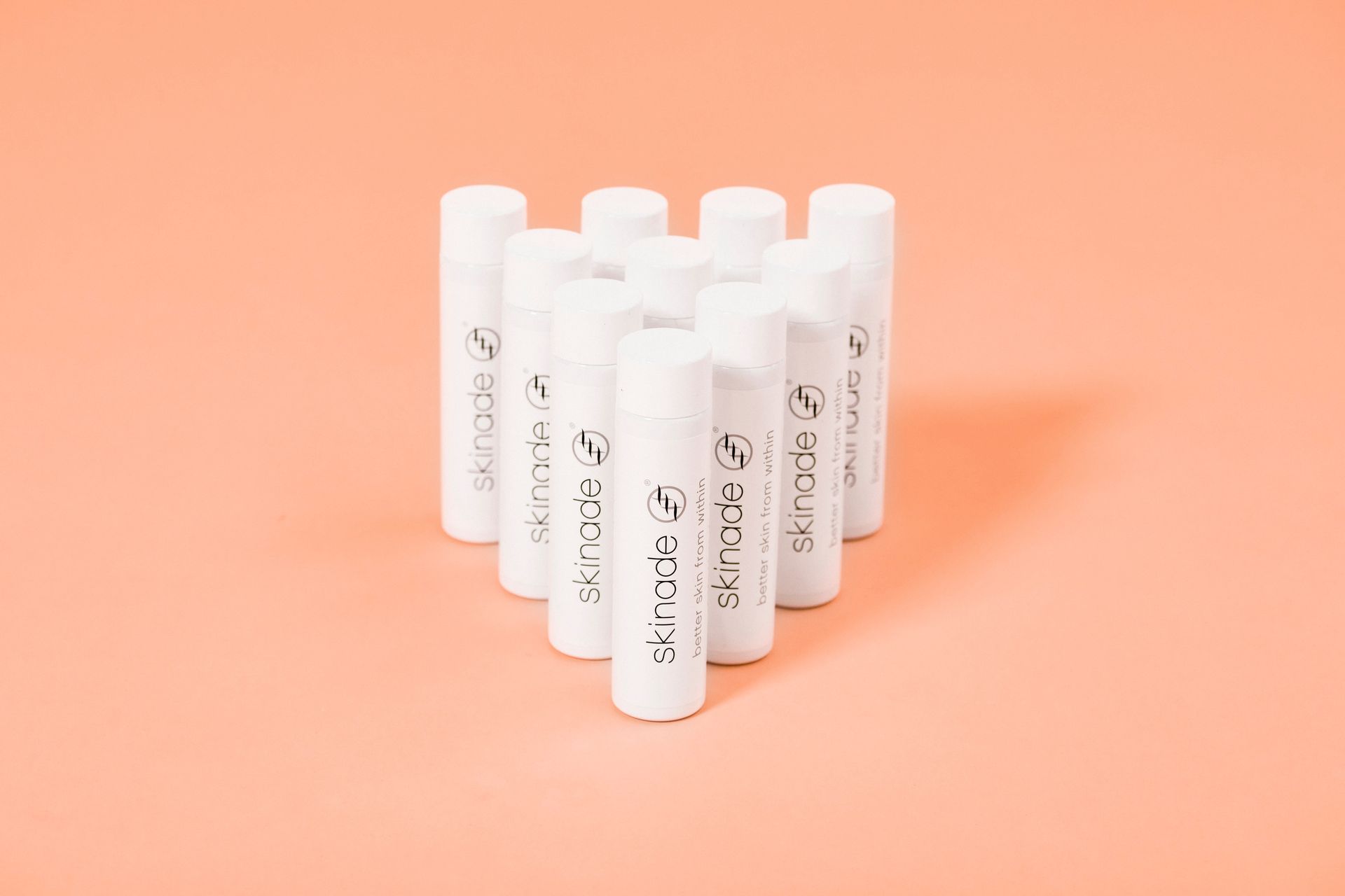 a group of lip balms are stacked on top of each other on a pink surface .