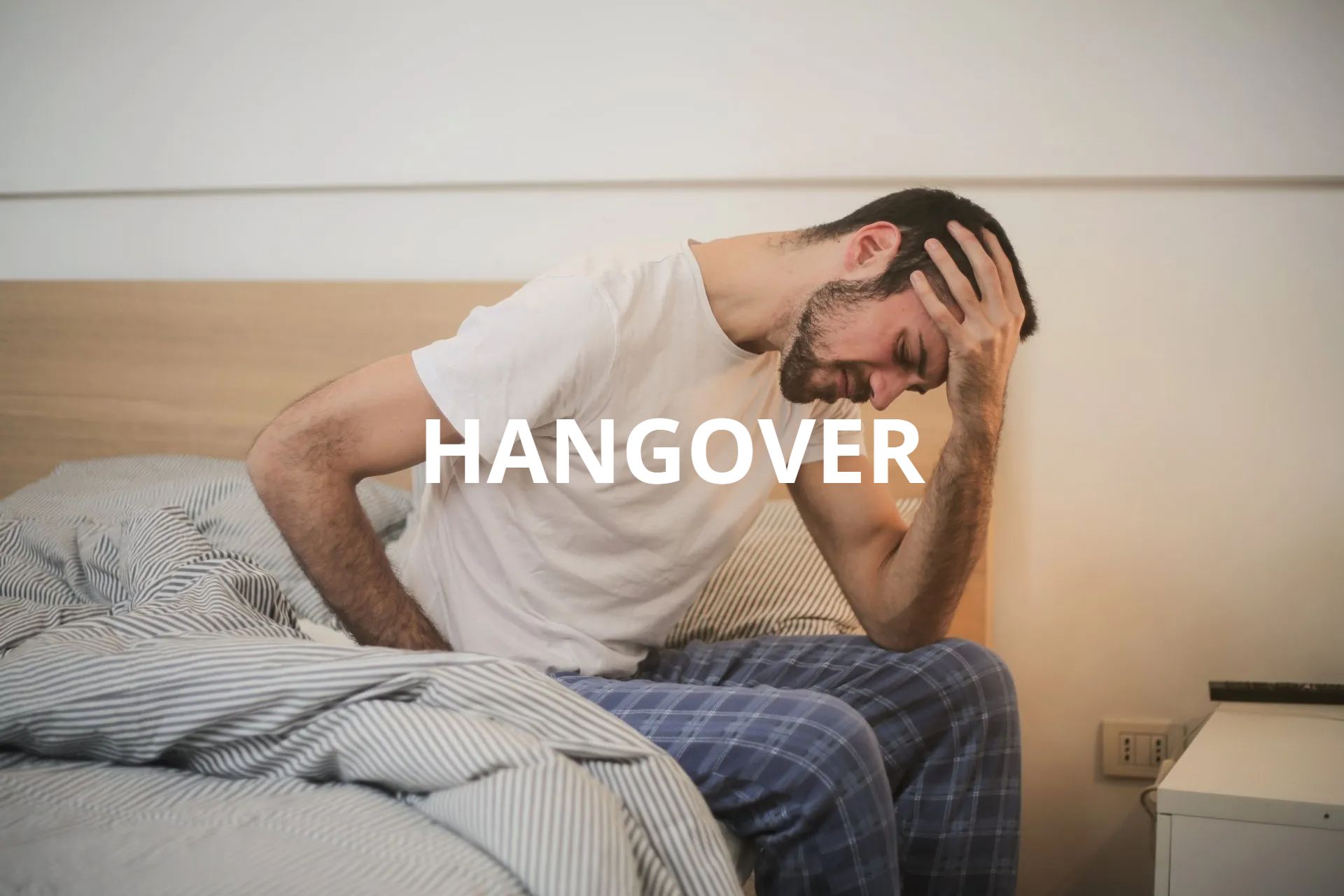 a man is sitting on a bed with his hands on his stomach .