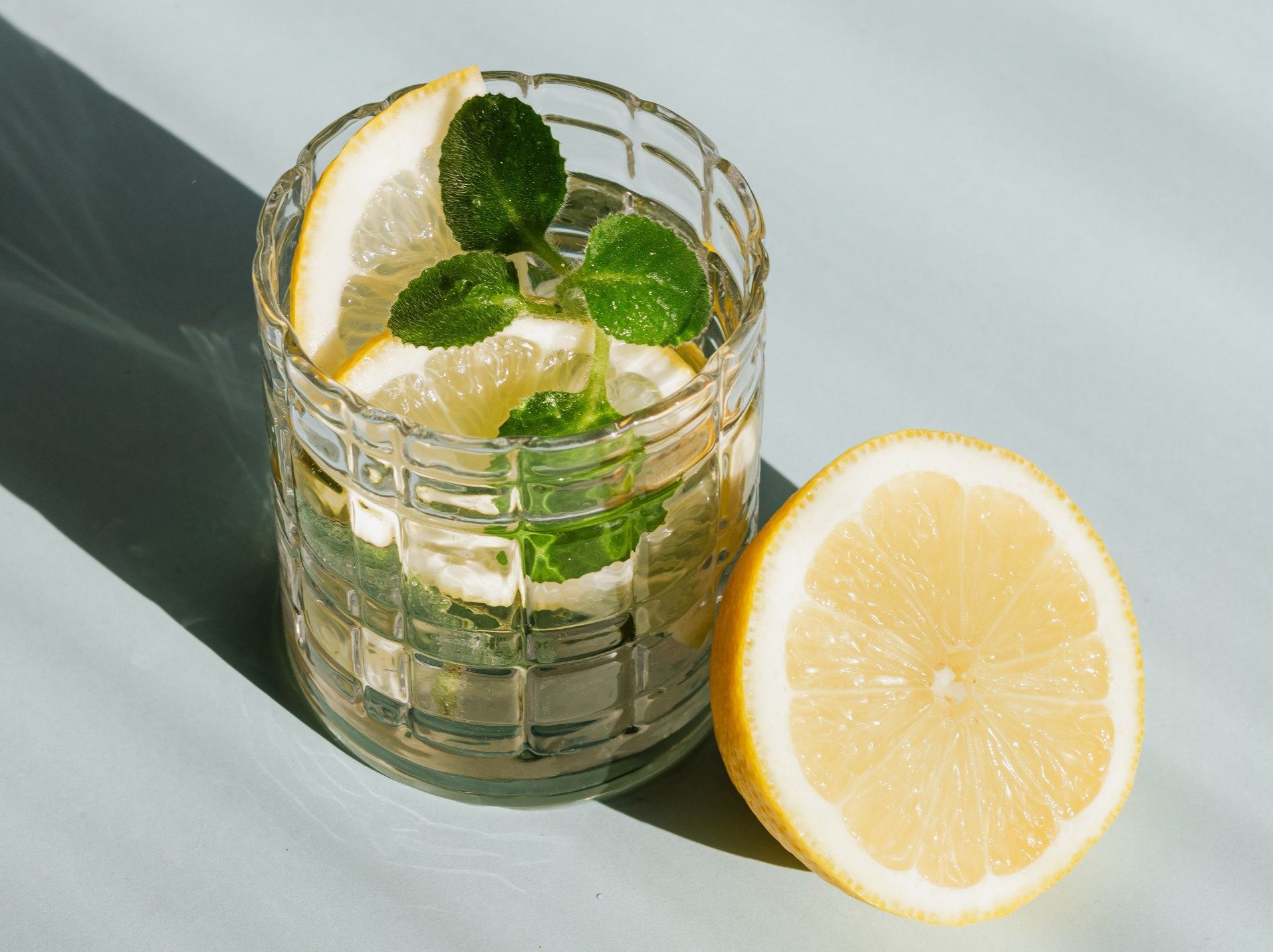 A glass of water with lemon slices and mint leaves