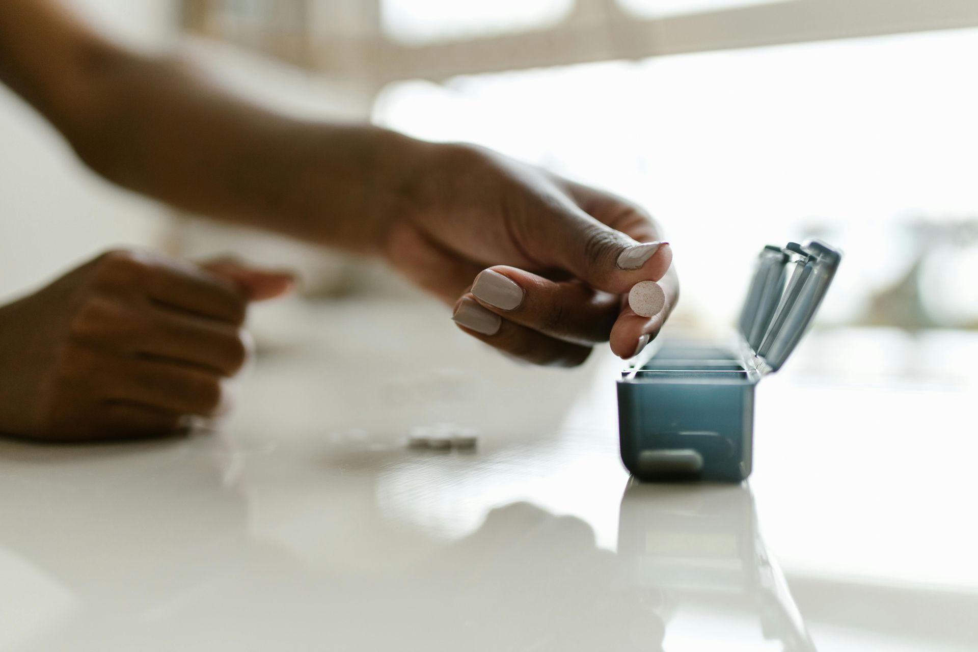 A person is taking a pill out of a pill box.