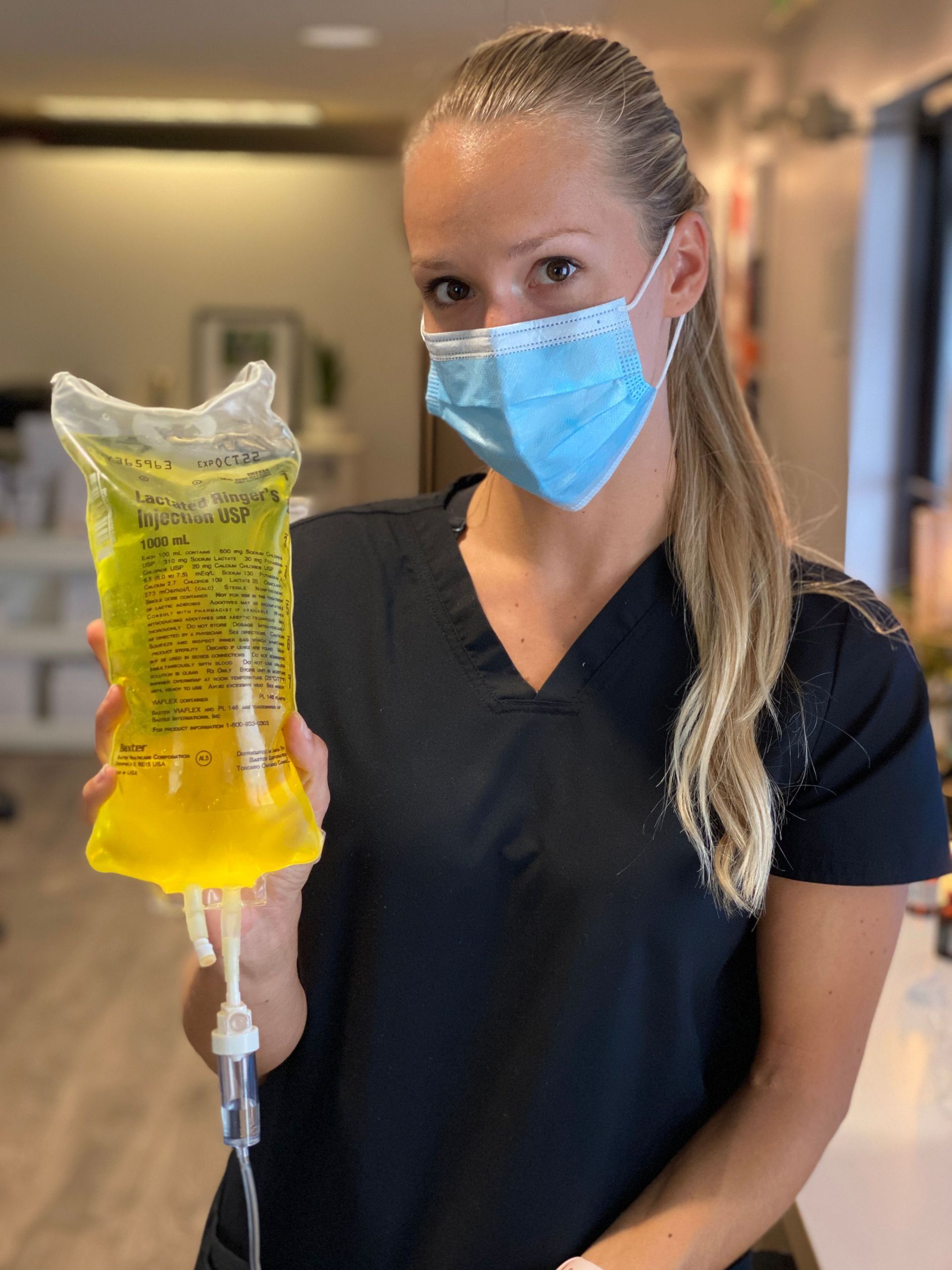 a woman wearing a mask is holding a bag of yellow liquid .