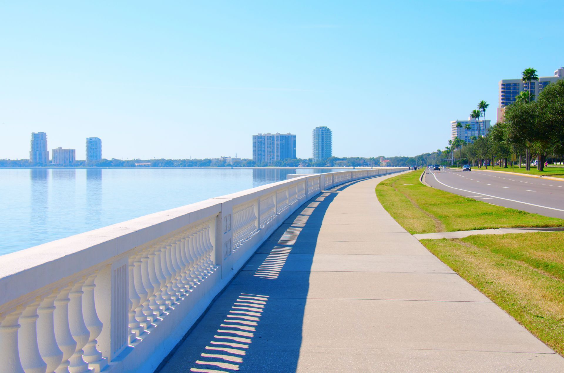 A walkway along a body of water with buildings in the background