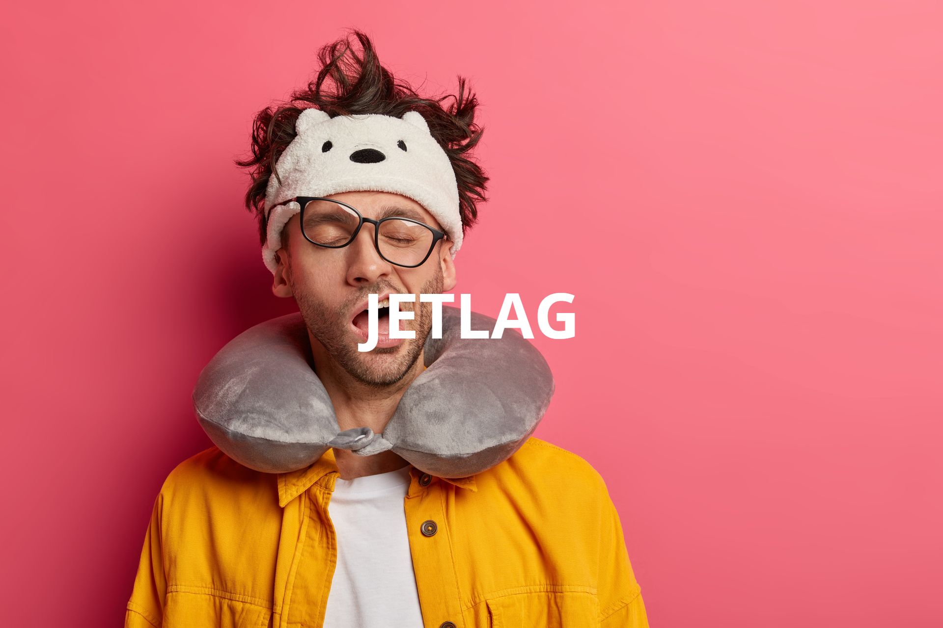 a man wearing a bear headband and a neck pillow with his eyes closed .