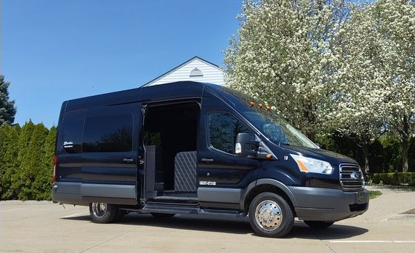 A black van is parked in a parking lot with its door open.