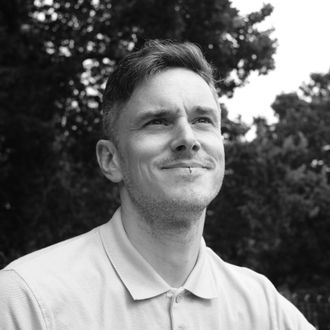 Black and white image of Steve Cross in light shirt against a dark background.