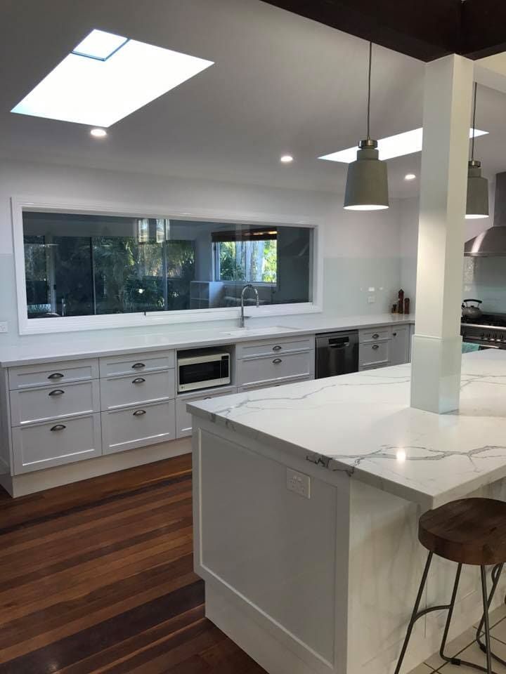 A Kitchen with White Cabinets, a Large Island, and a large Window — Ken Willis Joinery Pty Ltd In South Grafton, NSW