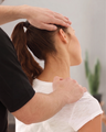 Therapist massaging a woman’s neck and upper back during a chiropractic treatment.