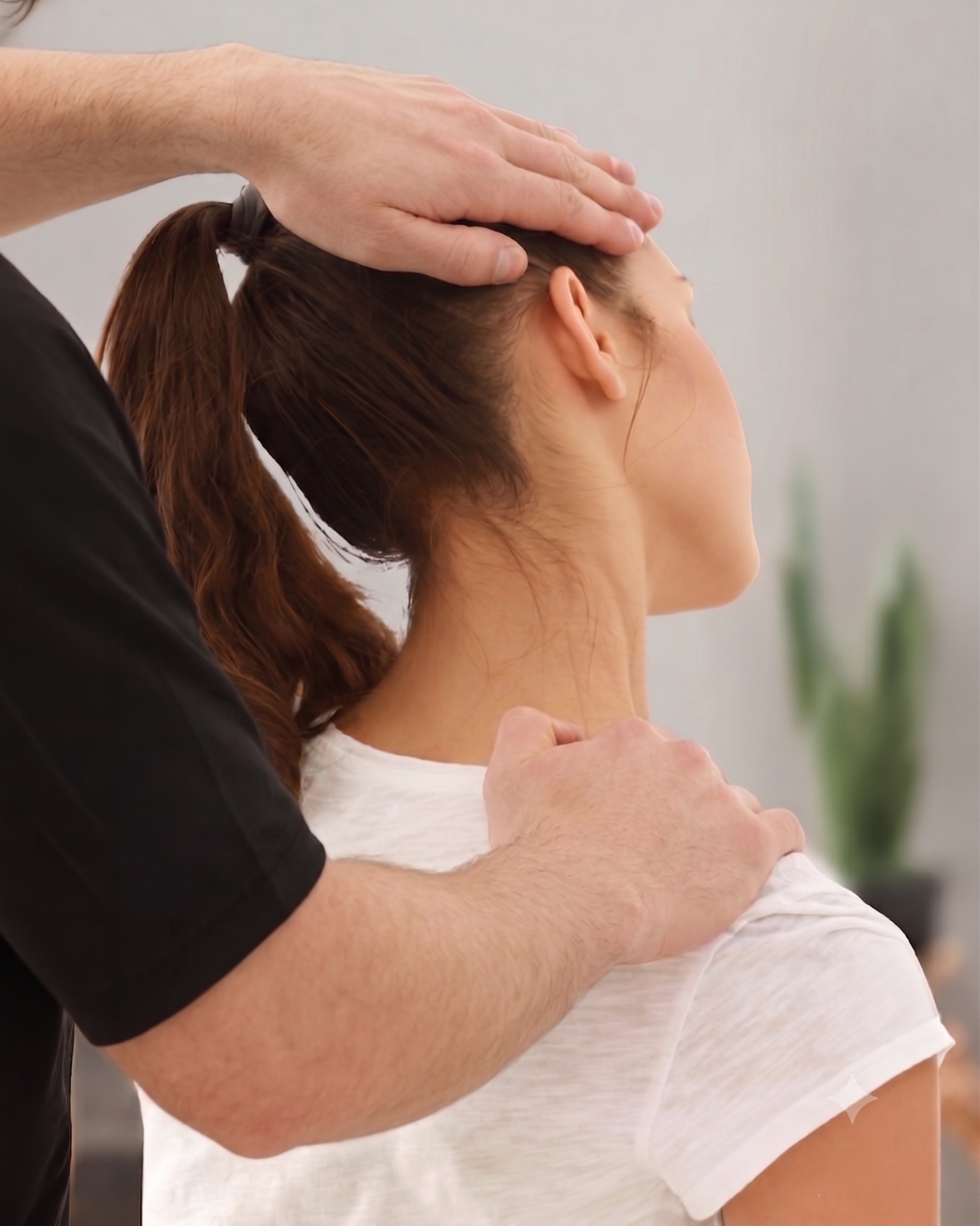 Therapist massaging a woman’s neck and upper back during a chiropractic treatment.