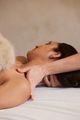 Person lying on a massage table receiving a neck massage from a therapist, close-up side view