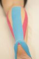Close-up of a leg with blue and pink kinesiology tape applied from thigh to ankle.