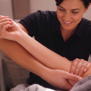 Woman smiling while giving a hand massage in a spa setting