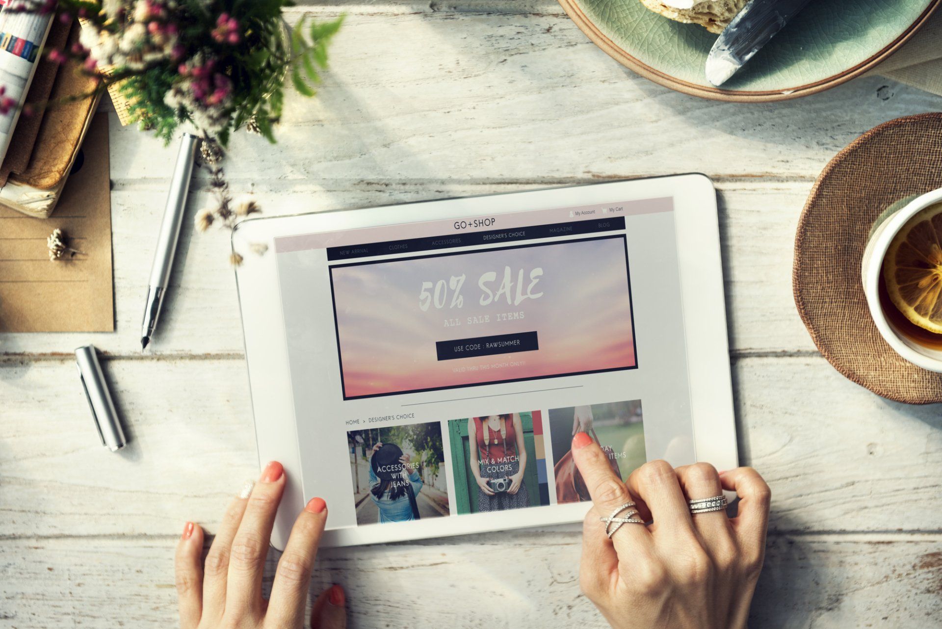A woman is using a tablet with a website on the screen that says it 's sale