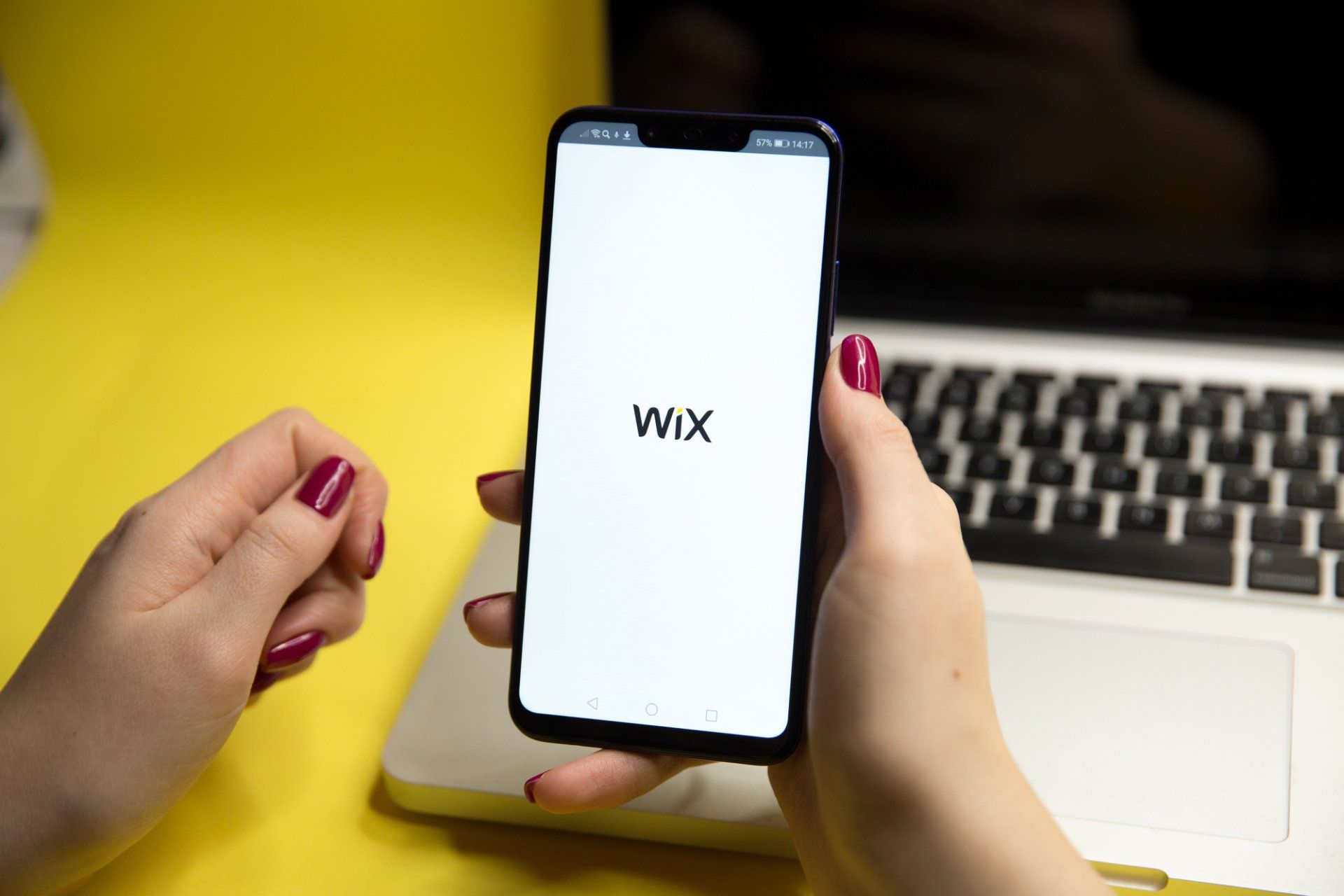 A woman is holding a cell phone that says wix on the screen
