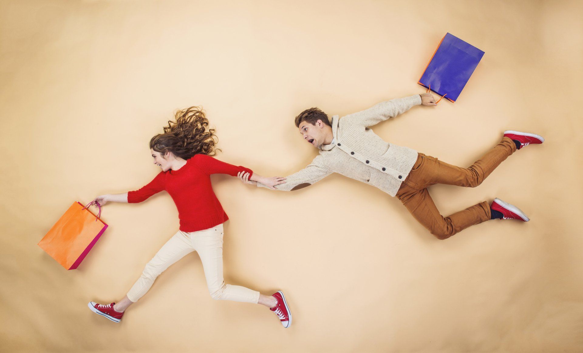 A man and a woman are running with shopping bags