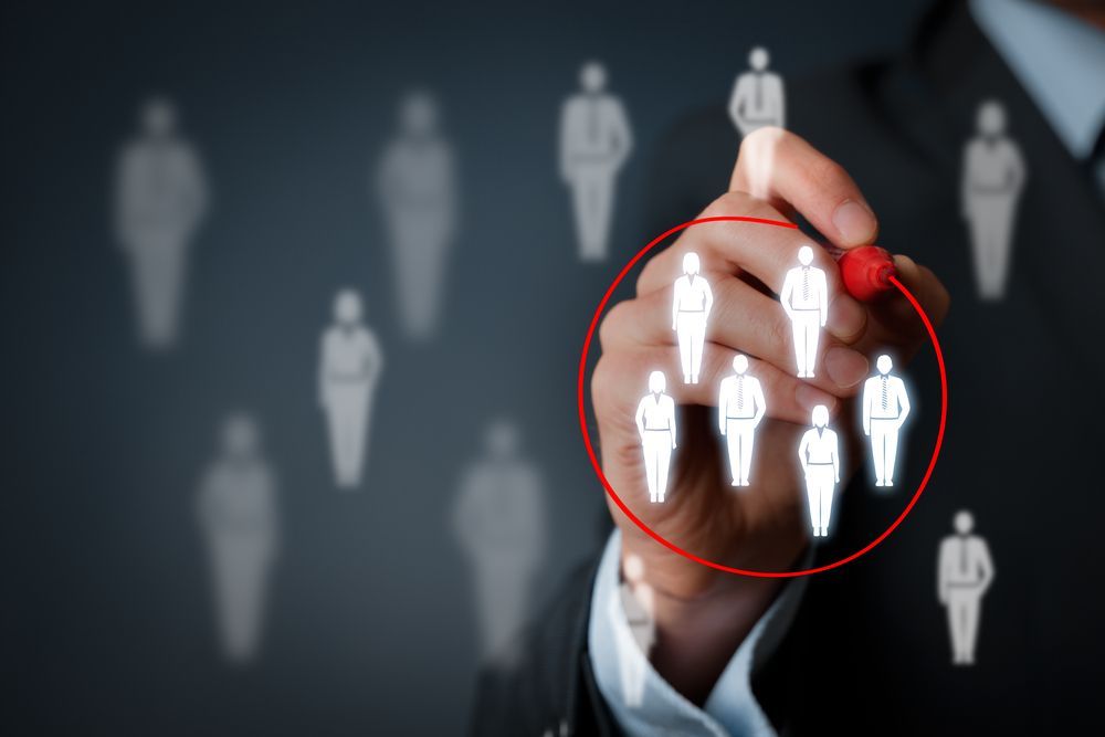 A man is pointing at a group of people with a marker.