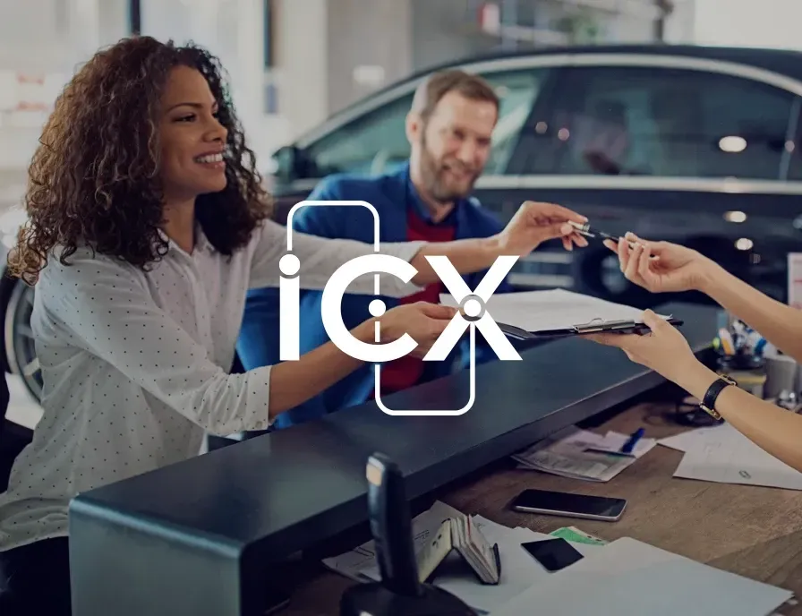 A woman is giving a man a car key at a car dealership.