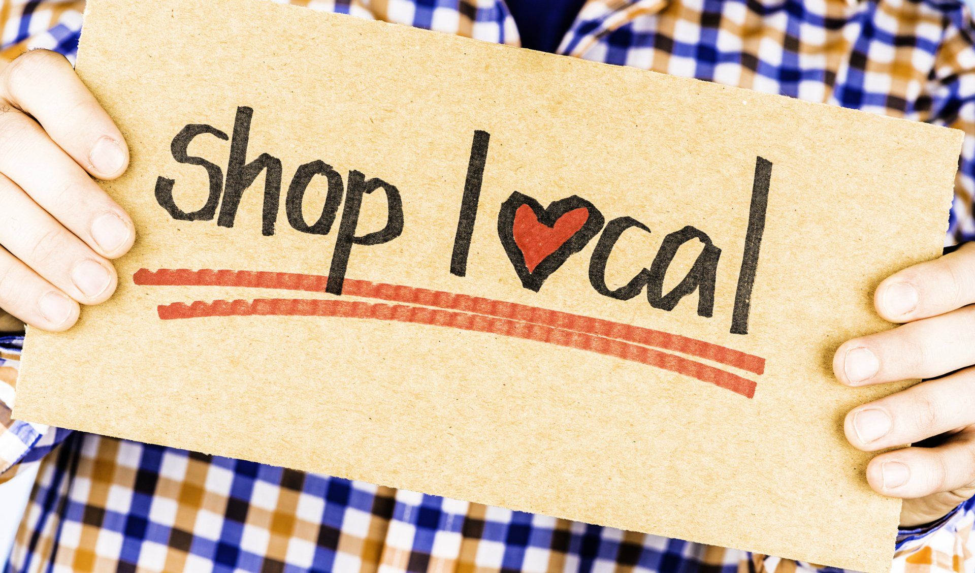 A person is holding a sign that says shop local