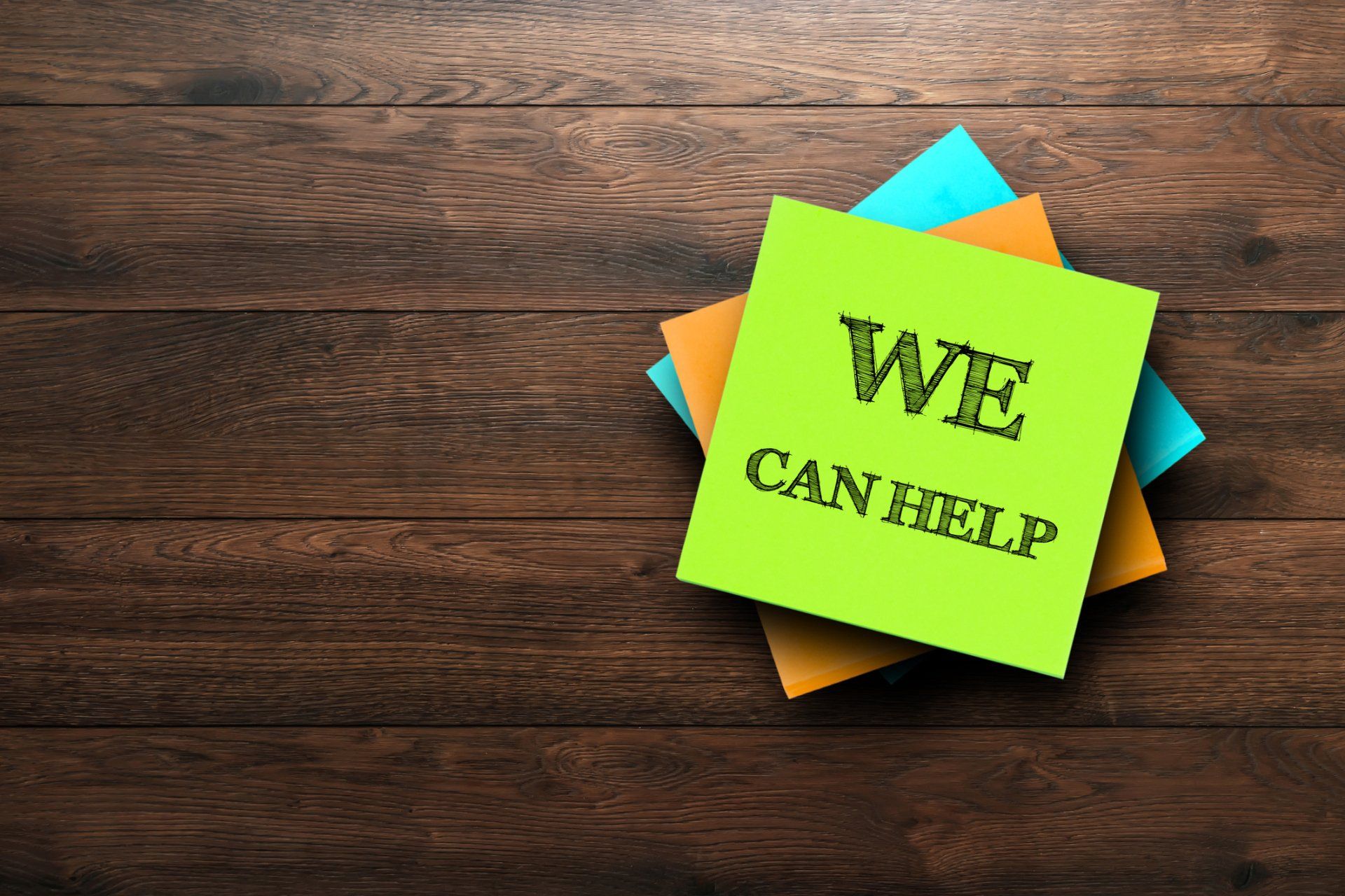 A stack of sticky notes with one that says we can help