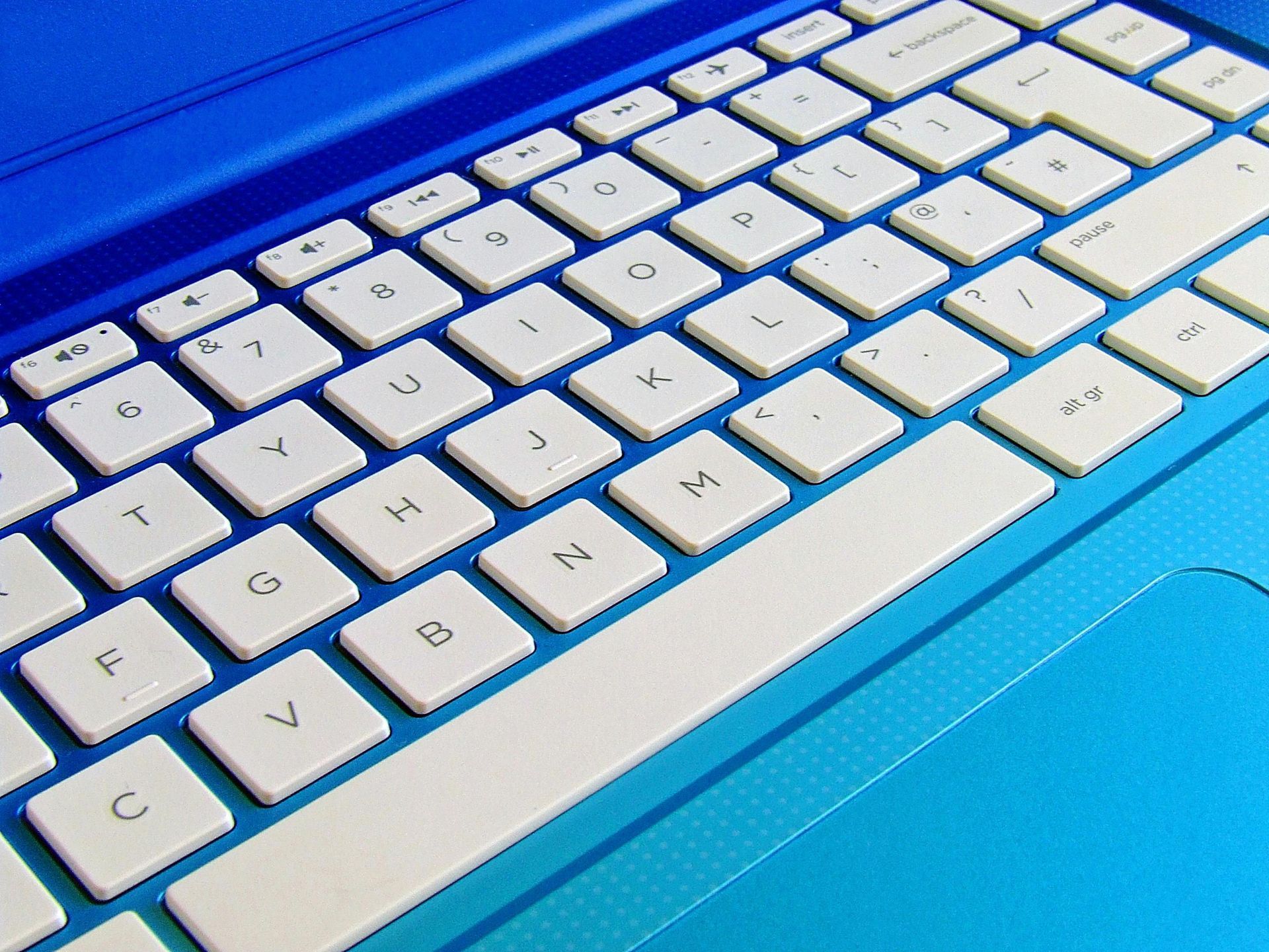A close up of a blue laptop keyboard with white keys