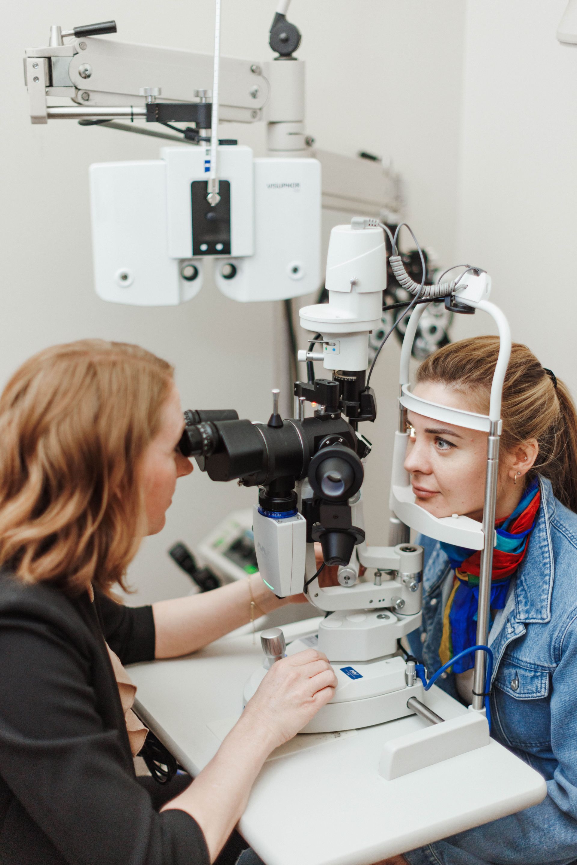 An optometrist uses a slit lamp to examine a patient’s eye during an eye exam in a clinical office setting.