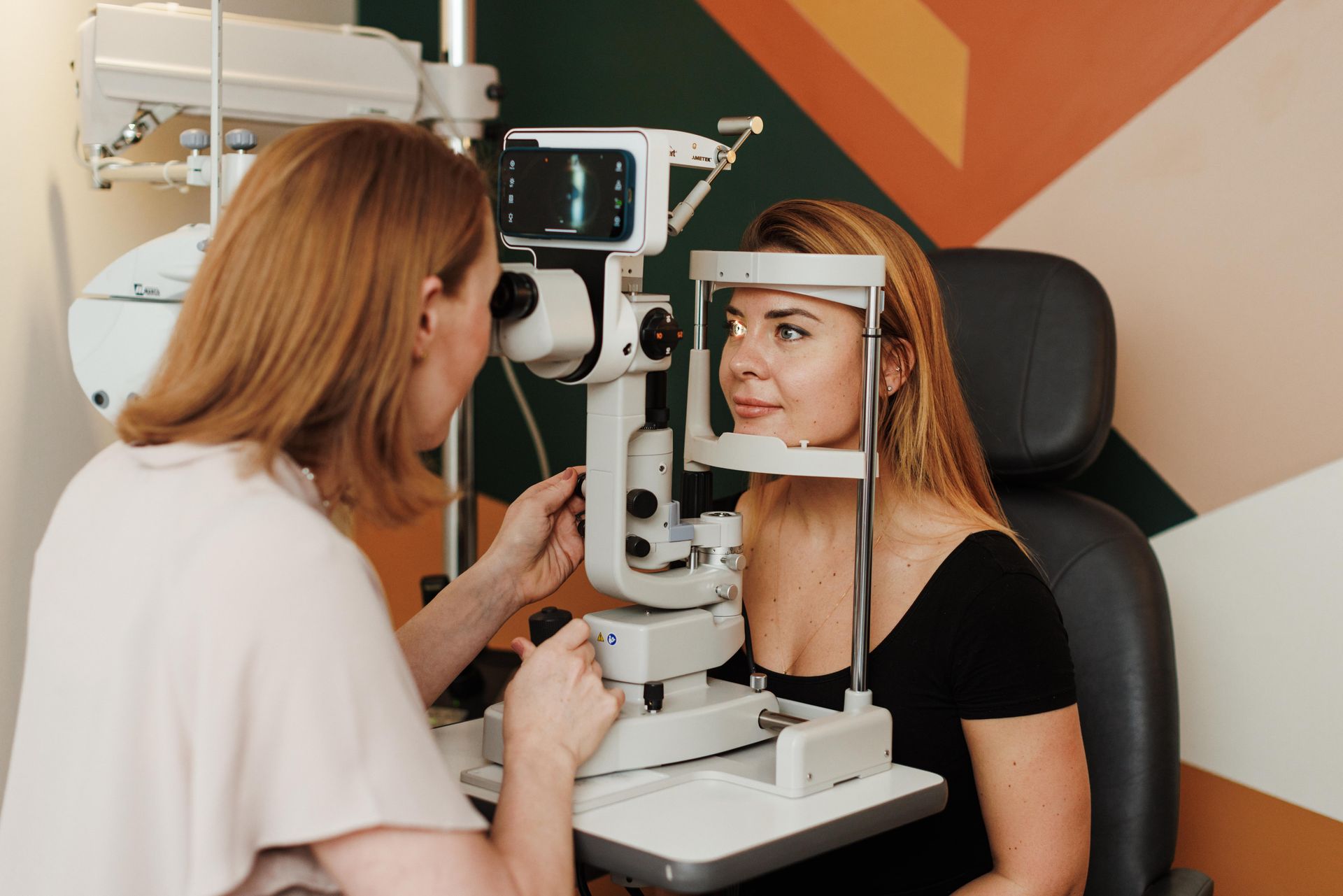 An eye care professional uses a slit lamp to examine a patient's eye in a clinical office.